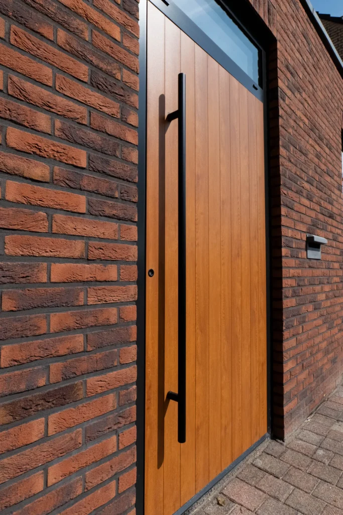 Detail van houten voordeur met lange zwarte greep